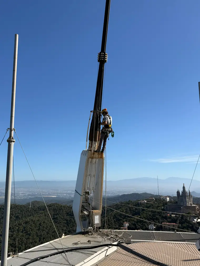 Técnico en mástil de antena sobre la ciudad